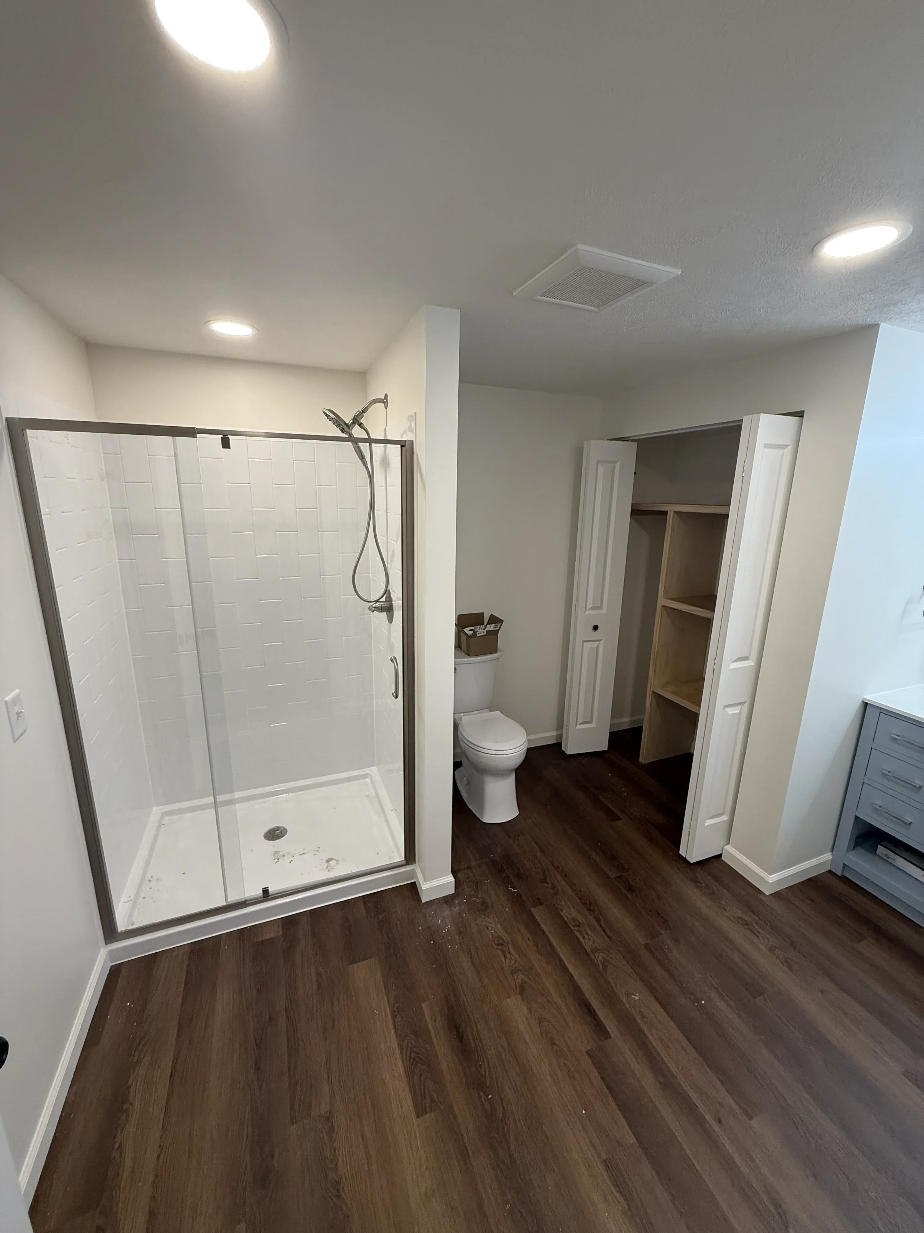 Completed bathroom remodel with walk-in shower, vanity, and hardwood-look flooring