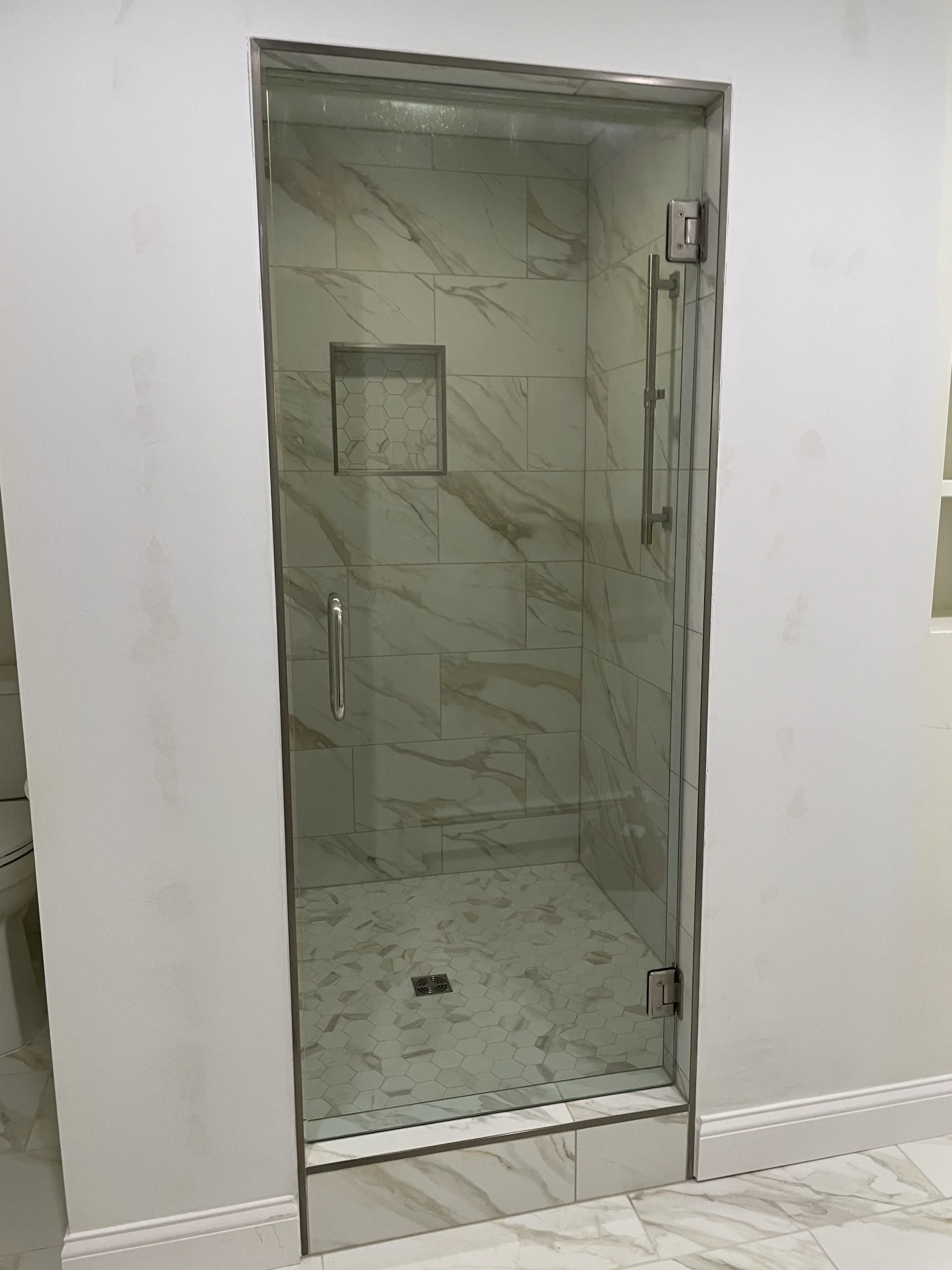 Marble tile walk-in shower with frameless glass door