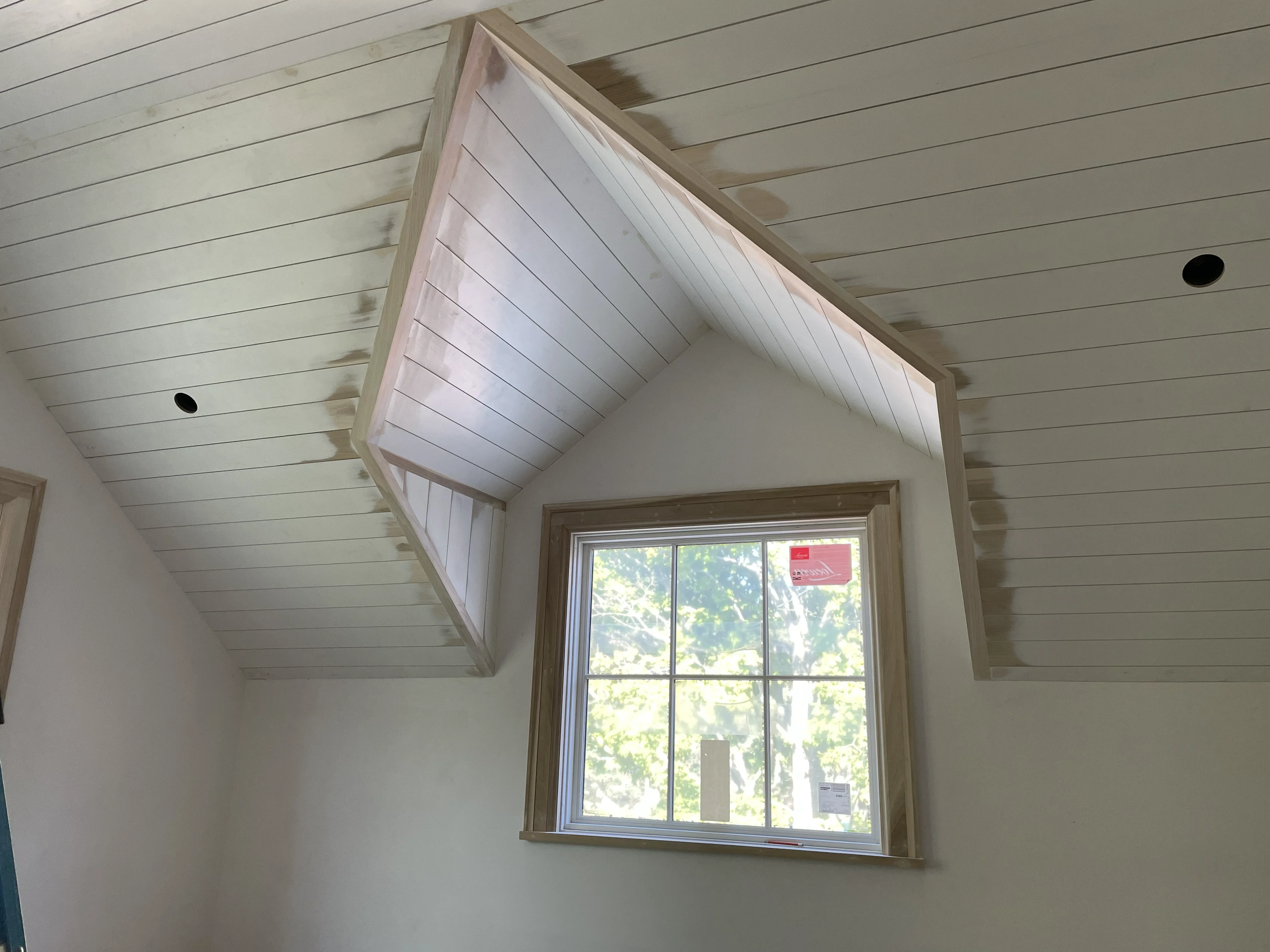 Vaulted shiplap ceiling with exposed rafter tails and gable window