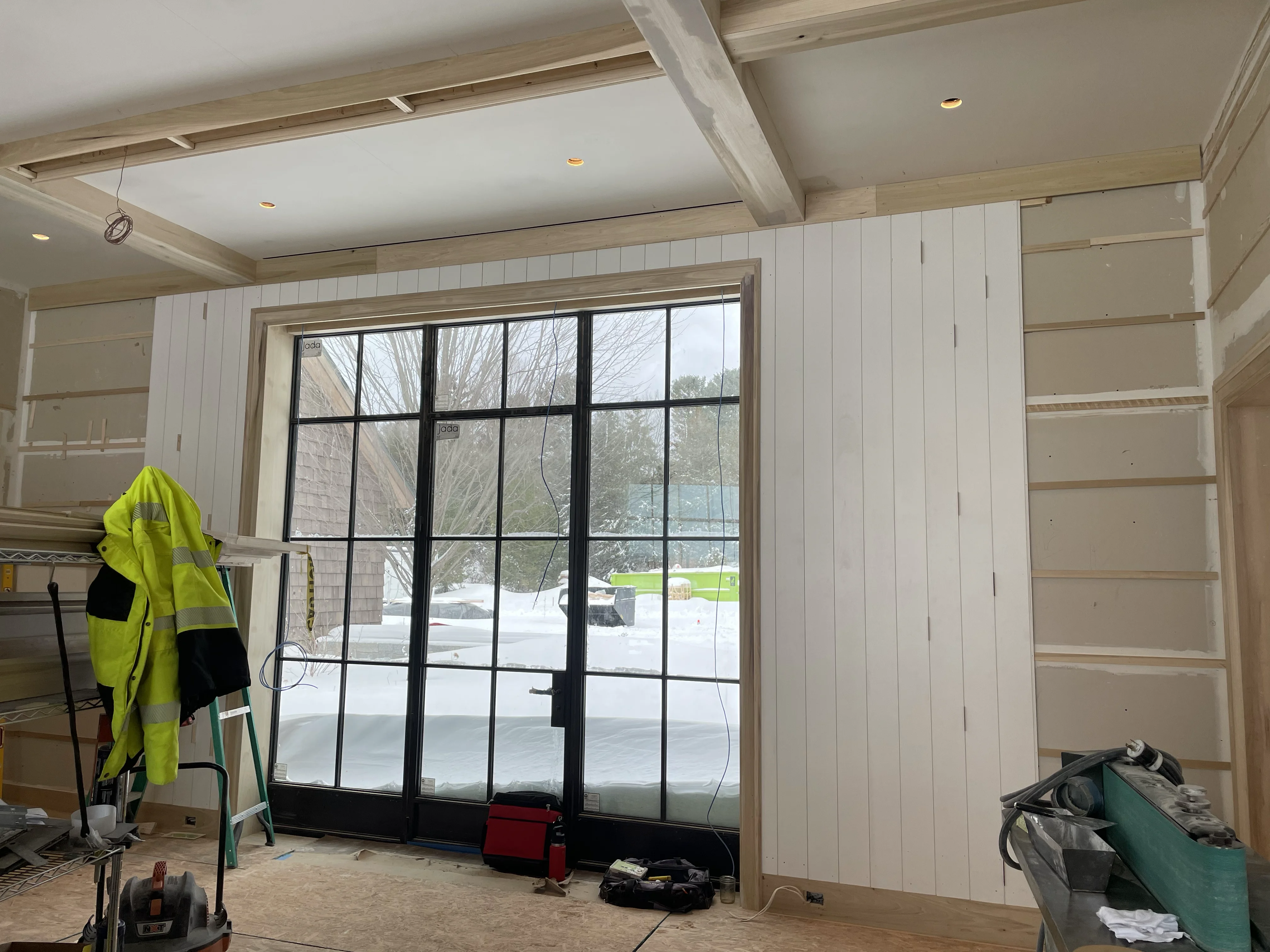 Large steel-grid window wall with shiplap interior and built-in shelving installed by Gerhard and Sons